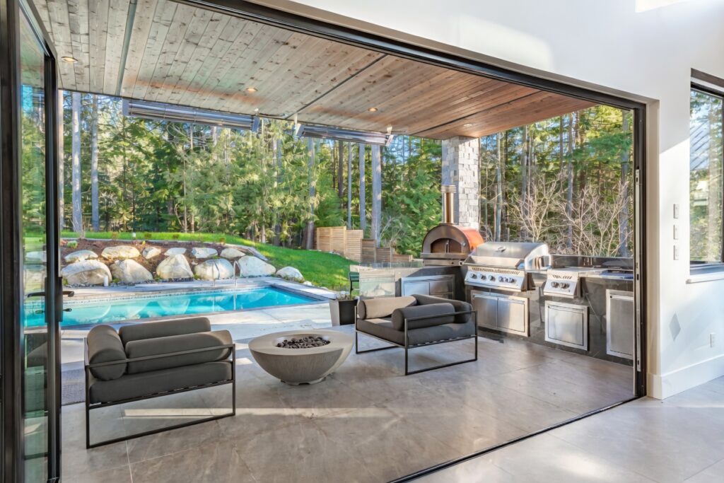 Outdoor kitchen and pool cost 2026 luxury indoor-outdoor living space with pool and modern furniture