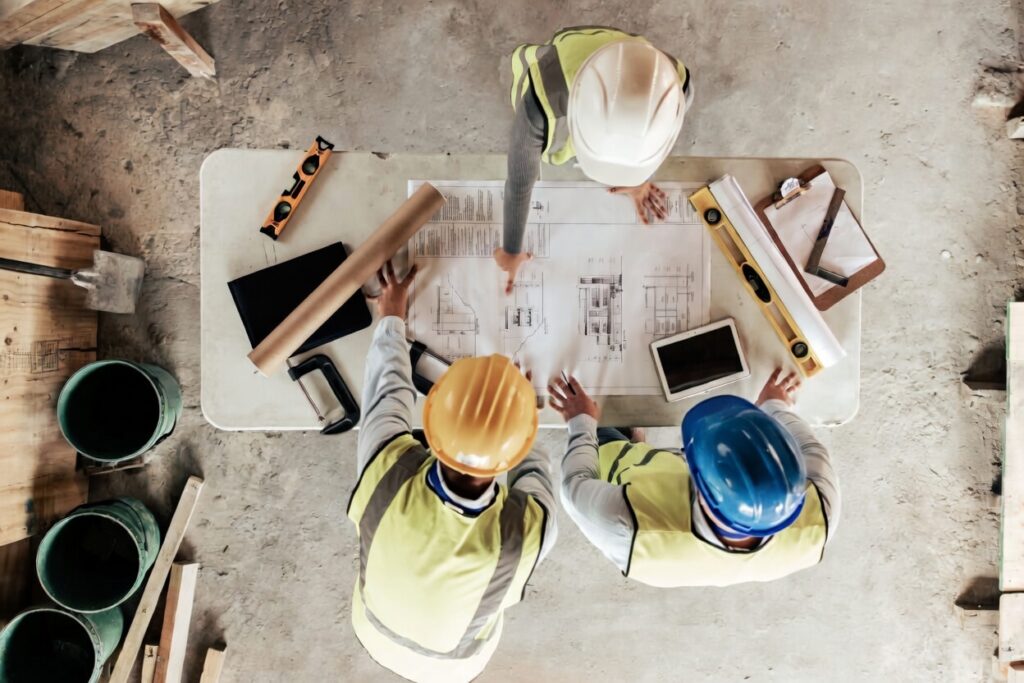 Commercial construction cost per square foot 2026 team of architects and engineers reviewing blueprints and plans on site